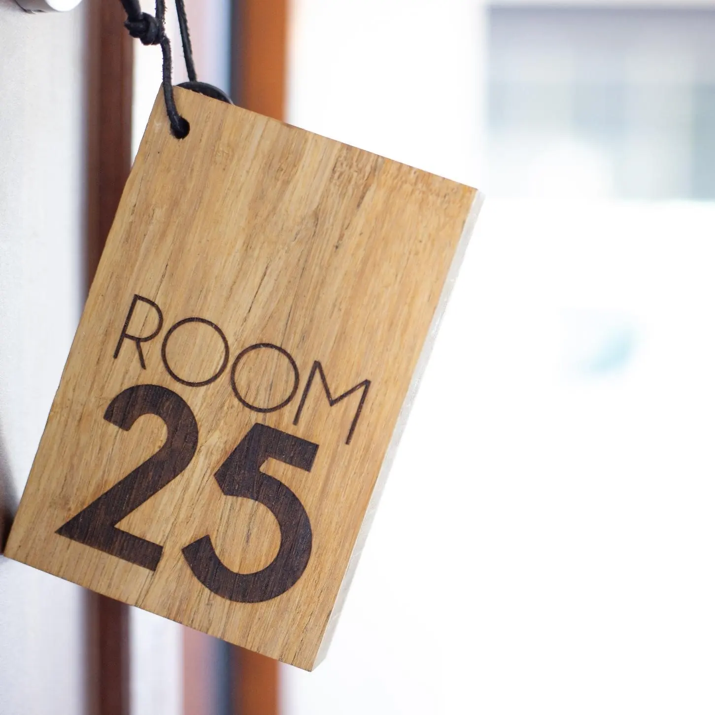 Houten sleutelhanger met ROOM25 aan de muur