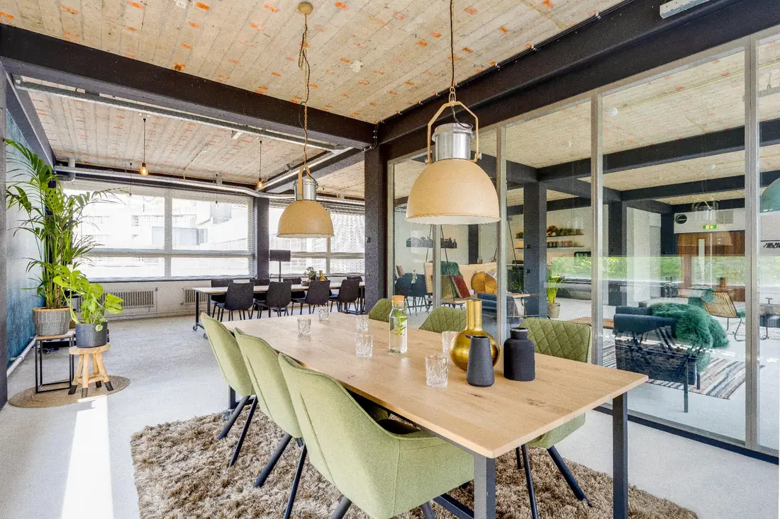 Vergadertafel met groene stoelen in de break-out ruimte van de Loft