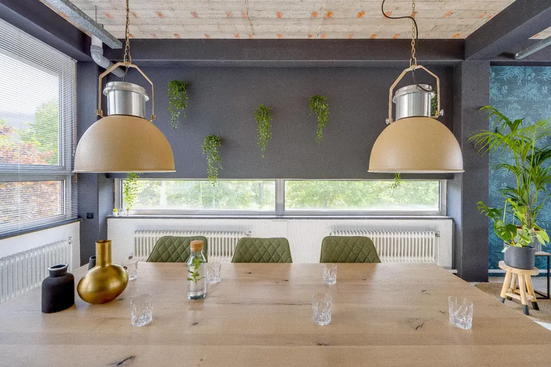 Houten tafel onder twee grote hanglampen in de Loft