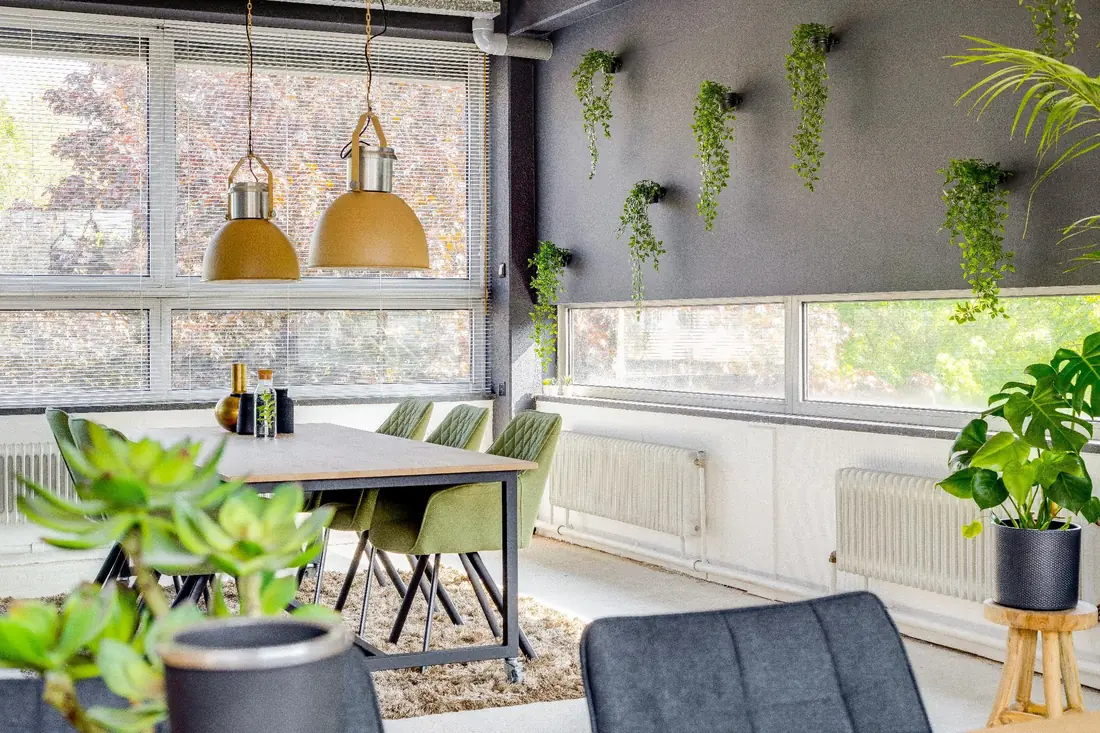 Tafel bij de ramen met planten en hanglampen in de Loft