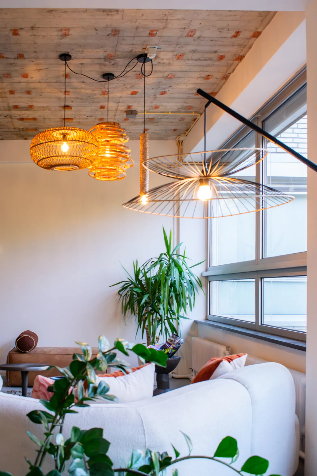 Rieten hanglampen boven de witte bank in de loungehoek van de Studio